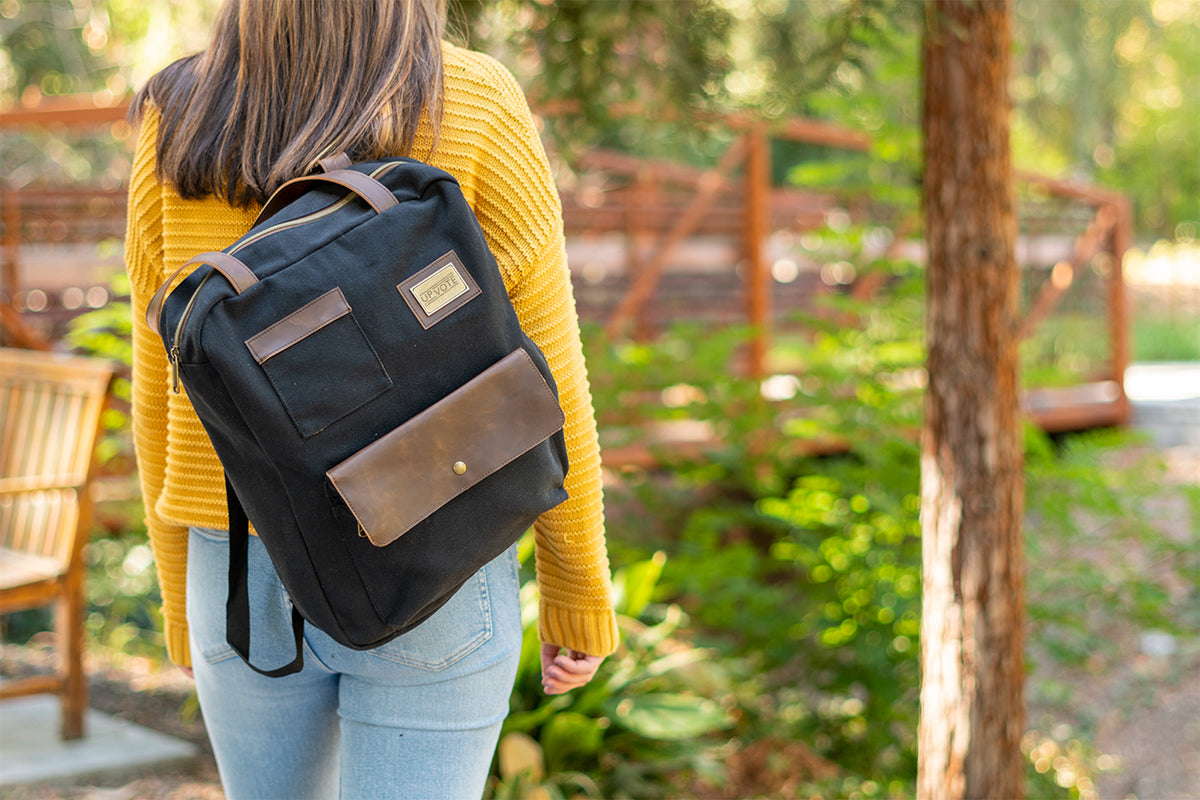 Person carrying a black canvas backpack, a popular employee gift