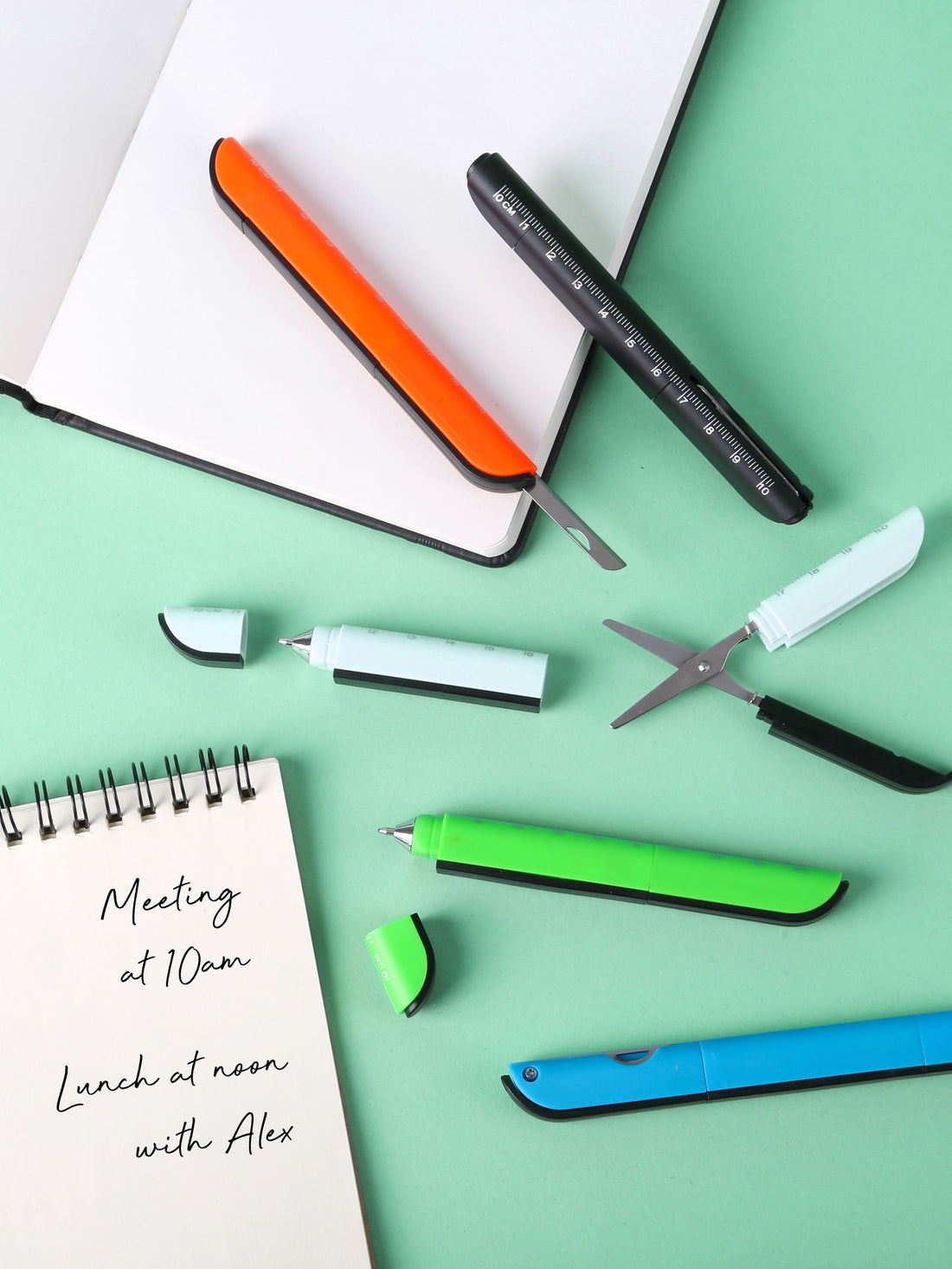 Notebook, pens, and multitools laid out on a mint background, ready to be chosen for a branded merchandise order